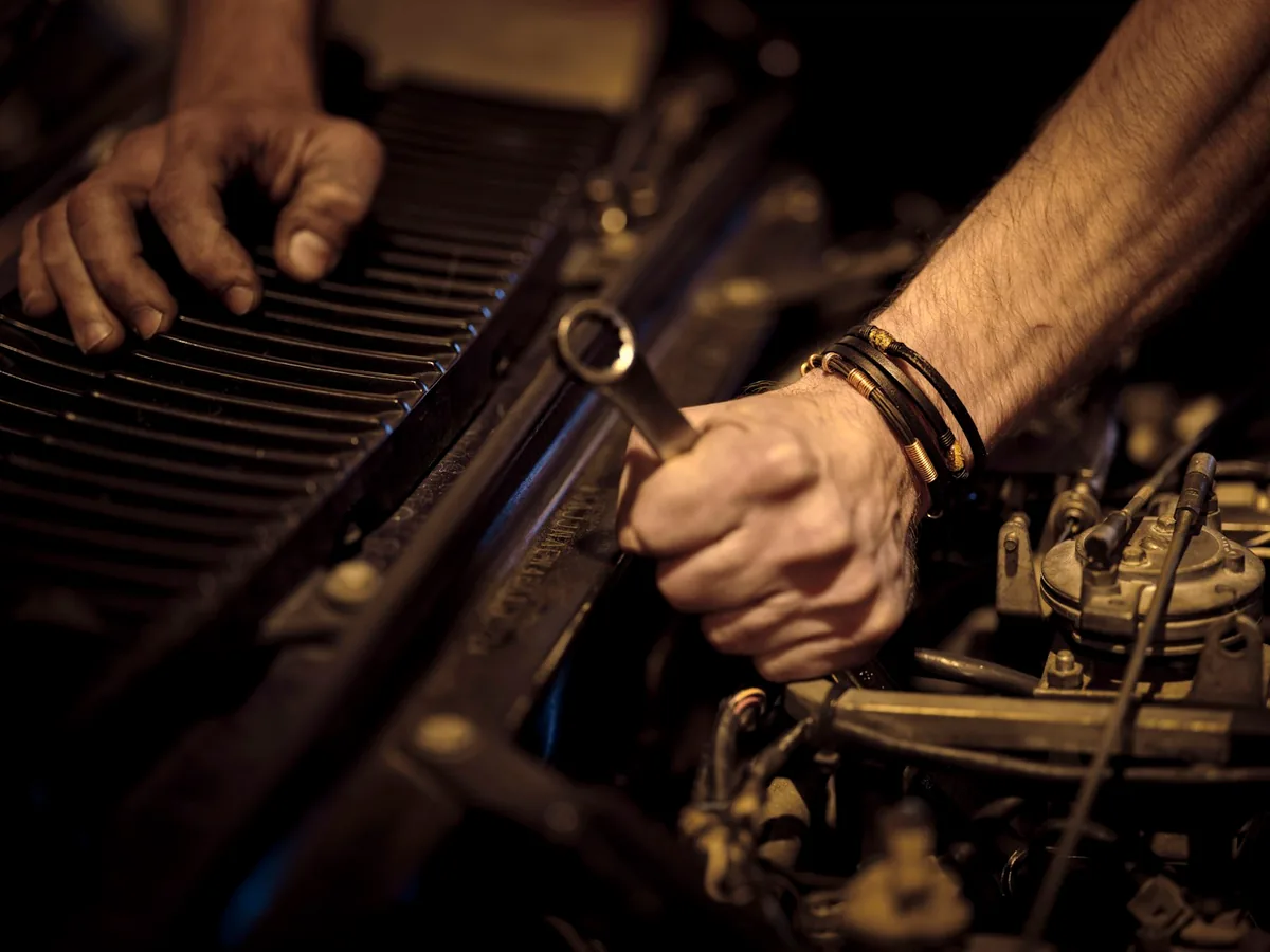 Hands with tools working on a car engine on a cold morning