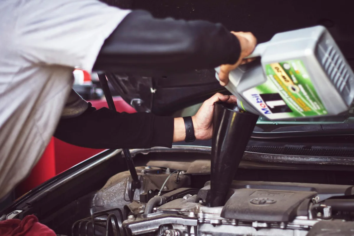 A person pouring fresh motor oil into a car engine